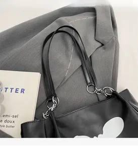 Close-up of black leather tote bag with silver chain straps and stylish white print