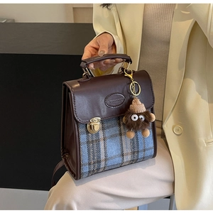 Detail of vintage tweed crossbody bag with leather flap and plush monster charm
