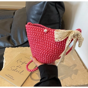 Detail of red and pink woven handbag featuring a large lace bow and elegant pearl buckle