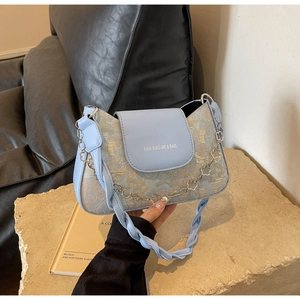 Détail du sac jacquard bleu clair avec chaîne florale argentée et logo de la marque