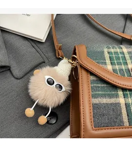 Green plaid crossbody bag with brown leather trim and cute plush bear charm detail