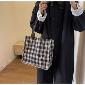 Detail shot of the black and white checkered woven fabric and reinforced handles on tote bag