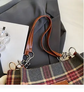 Detail of vintage plaid tote bag with smooth zipper closure and brown leather straps