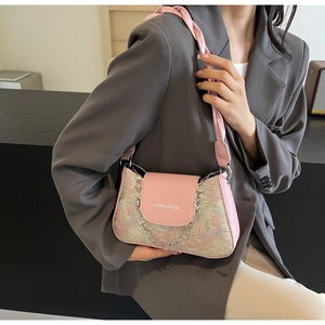 Détail du sac à bandoulière floral rose avec bandoulière tissée et chaîne trèfle