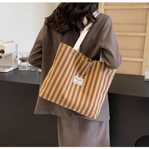 Detailaufnahme der braun gestreiften Canvas-Tasche mit cremefarbenen Trägern im Café