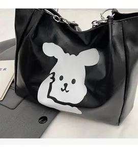 Detail of black leather tote bag featuring a white rabbit print and silver chain handle