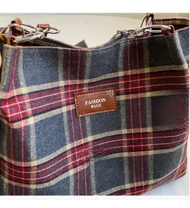 Detail of red and grey plaid tote bag showing thick wool texture and leather tag