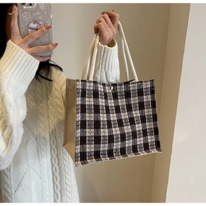 Detail of checkered woven tote bag with white rope handles and metal snap button closure