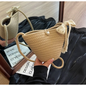 Macro shot of straw woven shoulder bag featuring lace bow and faux pearl buckle detail