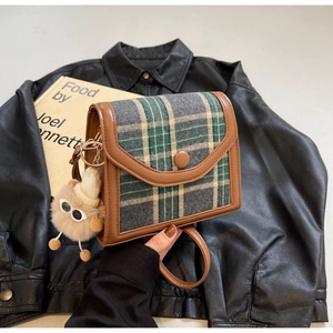 Detail of vintage wool plaid crossbody bag with brown leather trim and fuzzy eye charm