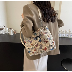 Detail of shoulder bag with butterfly prints and leather chain strap in a cafe setting