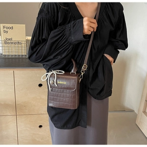 Detailed view of brown crocodile texture bag with pearl bow and heart charm