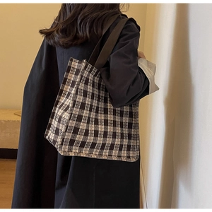 Detail view of a vintage checkered tote bag with wide straps for a stylish commute
