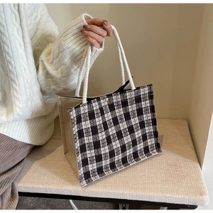 Detail of woven checkerboard tote bag with metallic magnetic clasp and rope handles