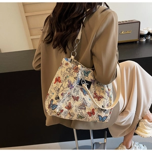 Fashionable tote bag with colorful butterfly prints and chain strap on a model shoulder