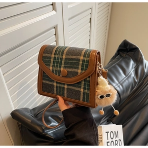 Detail of vintage plaid crossbody bag with brown leather trim and cute plush charm
