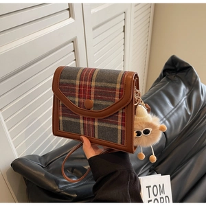 Detail of vintage plaid shoulder bag with brown leather trim and plush charm