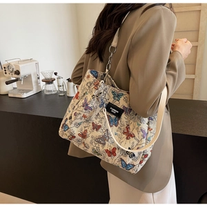 Detail of colorful butterfly embroidery on a beige tote bag with chic chain strap