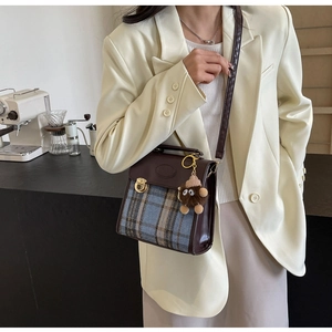 Retro plaid crossbody bag with brown faux leather trim and plush monster charm detail