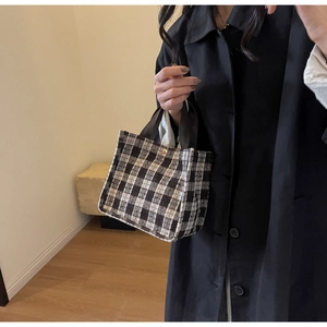 Close-up of black and white checkered tote bag with metallic snap button and handle