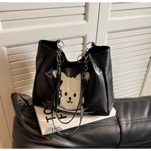 Detail of black leather tote bag with cartoon bear print and stylish chain shoulder strap