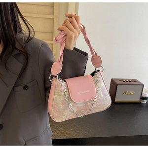 Détail du sac sous le bras en jacquard rose avec bandoulière et chaîne fleurie