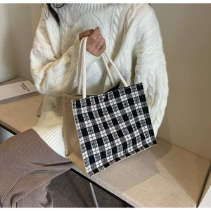 Detail of checkered tote bag with woven cotton rope handles and secure metal magnetic clasp