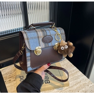Detail of vintage plaid handbag with brown leather trim and fuzzy monster charm