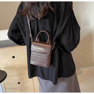 Detail view of brown crocodile texture mini square bag with gold metal hardware and strap