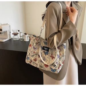 Detail of butterfly jacquard tote bag with leather strap and chain in a cafe setting