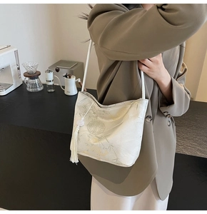 Dettaglio borsa a secchiello in jacquard bianco crema con motivi a bambù e nappa di seta