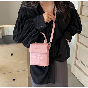 Detailed shot of pink crocodile pattern crossbody bag featuring a golden metal logo