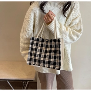 Close-up of black and white checkered canvas tote with woven rope handles and metal snap button