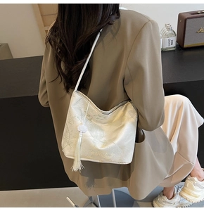 Dettaglio della borsa a secchiello jacquard crema con motivi a nuvola e lunghe nappe