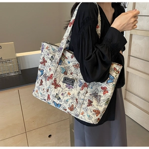 Detail of large canvas tote bag featuring colorful butterfly prints and fashion label