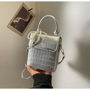 Detail of silver crocodile pattern texture on a mini bag with a pearl heart charm