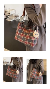 Close-up of retro plaid tote bag with brown leather strap and cute plush pendant