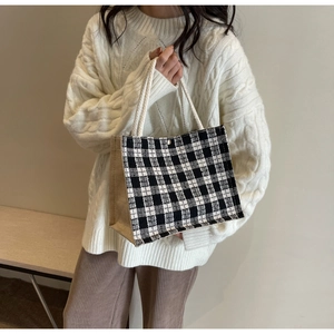 Detail of checkered canvas tote bag with rustic rope handles and jute side panels