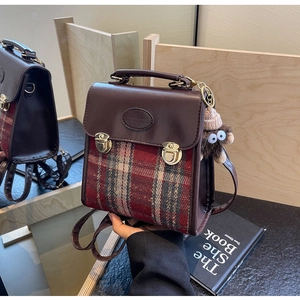 Detail of retro plaid backpack with brown leather lid, gold buckle and plush pendant