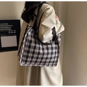 Chic houndstooth tote bag with brown webbing strap shown on a model for daily use
