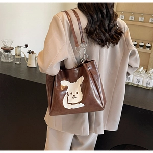 Detail of dark brown tote bag with white cartoon rabbit and metal chain strap