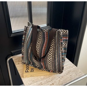 Detail of bohemian woven tote bag with colorful ethnic stripes on marble surface