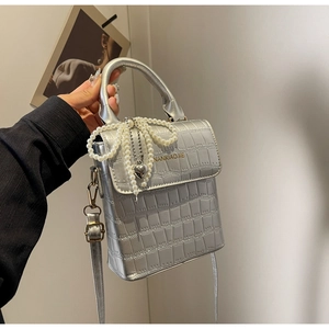 Detail of silver crocodile pattern bag with pearl bow and heart metal pendant charm