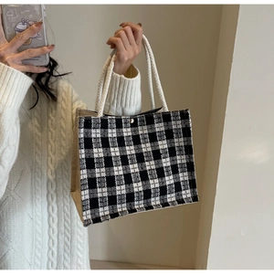 Detail of black and white checkered woven bag with cotton rope handle and gold buckle