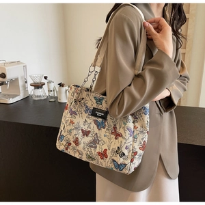 Detail of butterfly jacquard tote bag with chain strap in a cozy cafe setting