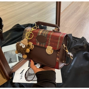 British retro handbag featuring red plaid fabric with brown leather and gold push-locks