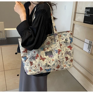 Detail of a large canvas tote bag with butterfly prints and fashion label on shoulder