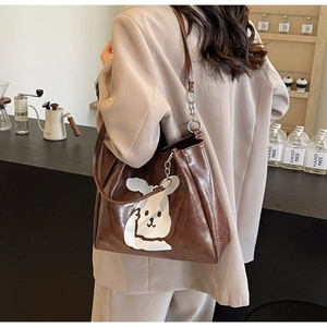 Detail of large brown tote bag featuring cartoon bunny print and stylish metal chain link