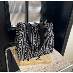 Detail of large woven ethnic tote bag with geometric diamond patterns and wide straps