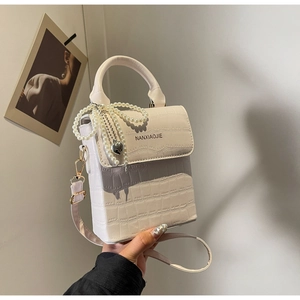 Detailed view of white crocodile pattern box bag with pearl chain and heart pendant